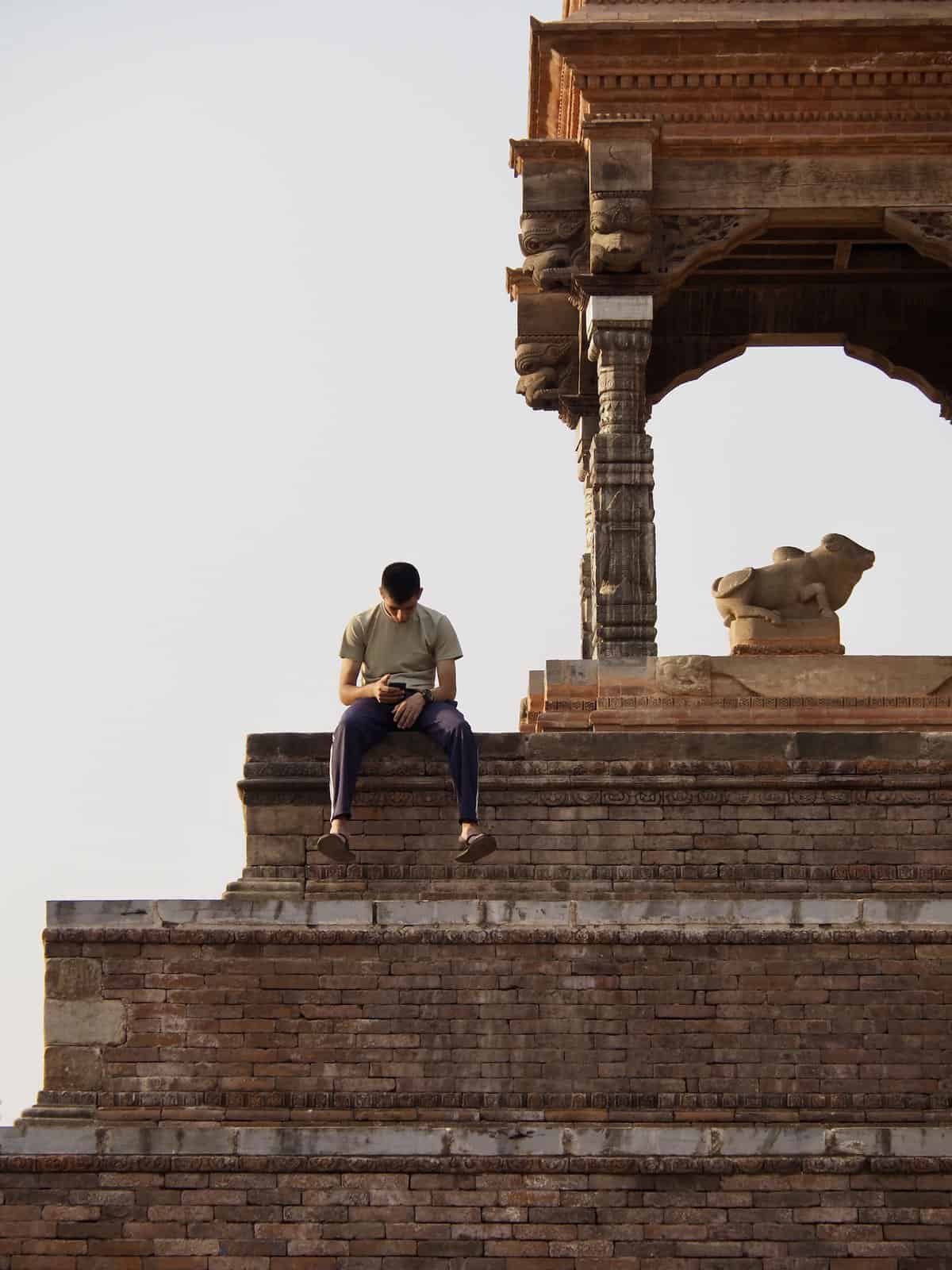 A boy sits on the upper step of an ancient temple in Bhaktapur Durbar Square, Nepal.