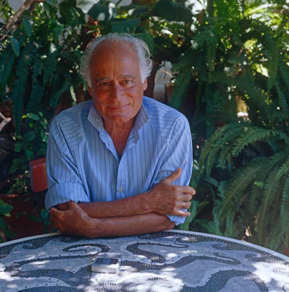 Portrait of interior designer John Stefanidis sitting in the garden of his holiday home in Patmos.