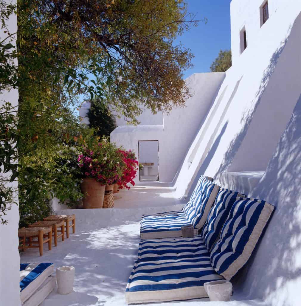 Blue and white striped floor cushions leaning against a slanting wall of the house form a comfortable and informal seating area on one of the many terraces of John Stefanidis' home in Patmos.