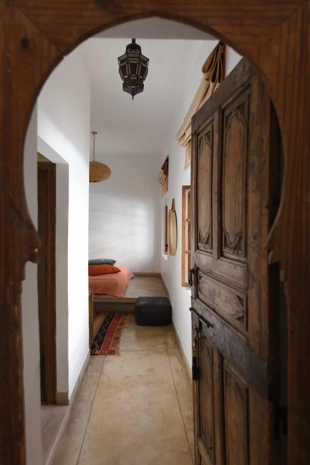 Riad UP. View through keyhole wooden door to Double Room, with platform bed, Moroccan lantern and Berber rug, Riad UP, Marrakech.