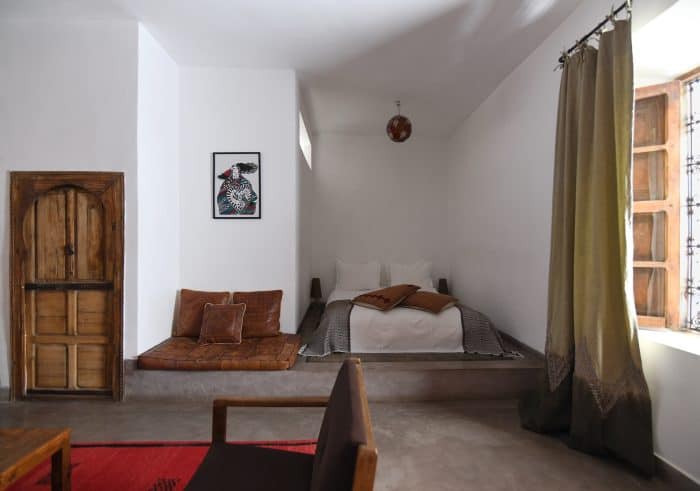 Junior Suite with low bed, leather cushions, embroidered curtain, YSL artwork and antique wooden door, Riad UP, Marrakech.