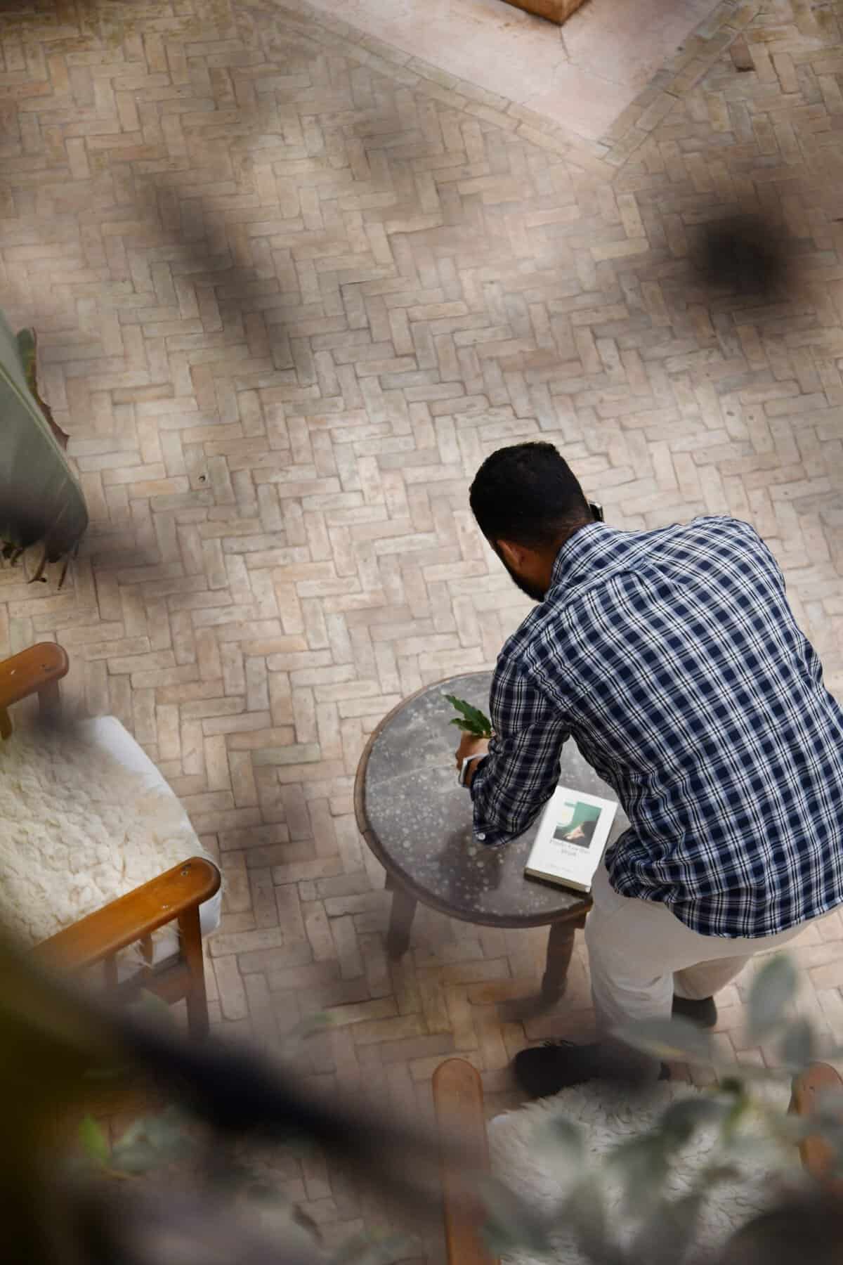 Riad UP. Elsa's assistant Khalid places a vase of frech flowers on a table in the courtyard, Riad UP, Marrakech.
