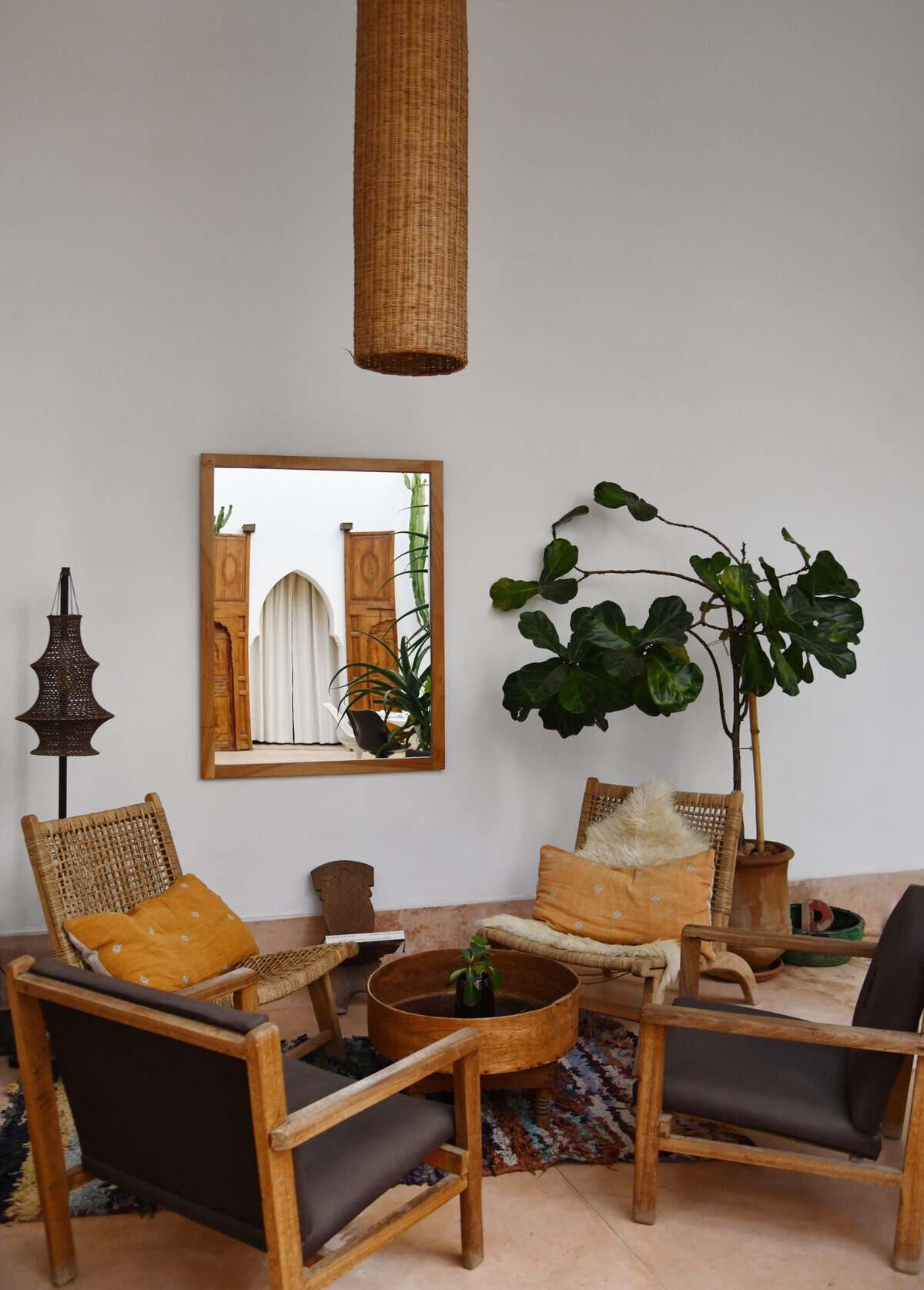 Riad UP. Courtyard lounge area, wooden armchairs, boucherouite rug and ficus tree, Riad UP, Marrakech.