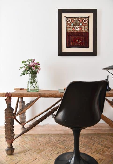 Tulip chair by Eero Saarinen, table made from Tuareg tent pegs, vase of dahlias and framed Berber artefact in the entrance hall, Riad UP, Marrakech.