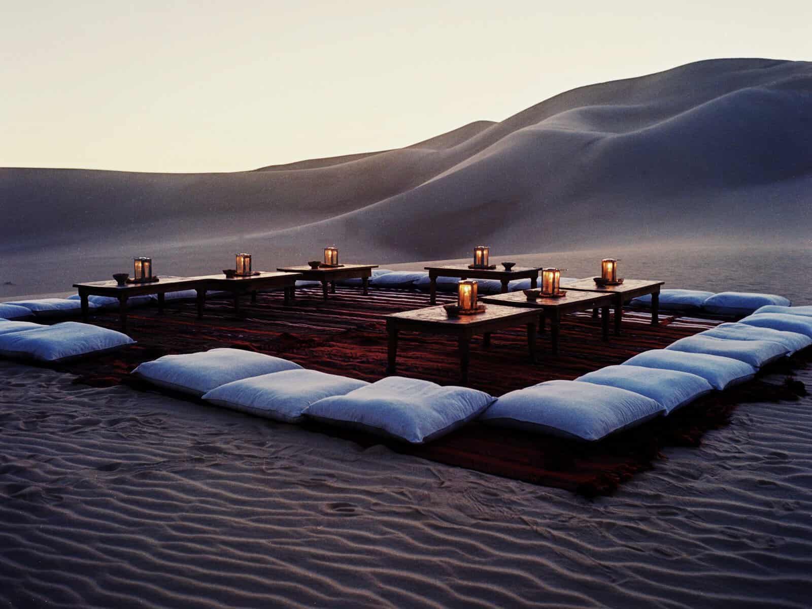 Tables with cushions and candles for a desert dinner at Adrere Amellal in Siwa, Egypt.